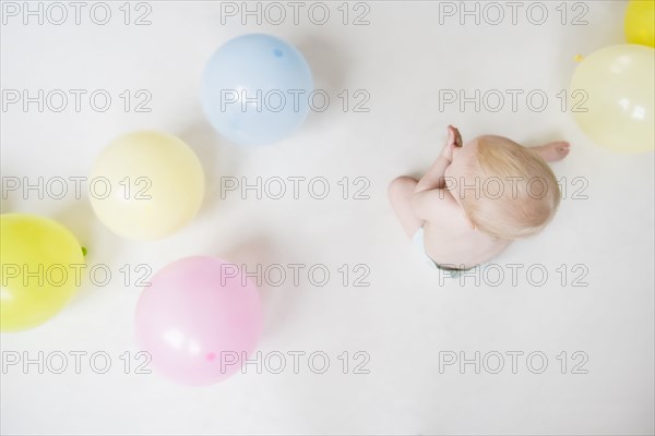 Caucasian baby boy sitting on floor with balloons