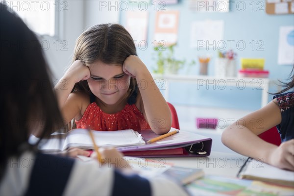 Frustrated girl staring at notebook in school