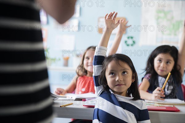 Girls raising hand for teacher in classroom