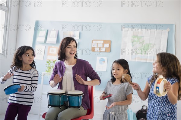 Teacher and girls playing bongos and tambourines in classroom