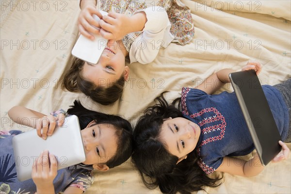 Girls laying on blanket using cell phone and digital tablets