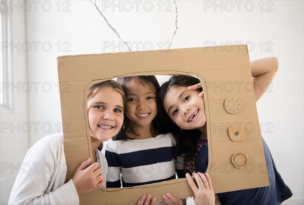 Portrait of smiling girls holding cardboard television