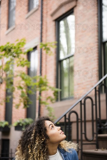 Curious Mixed Race woman looking up in city