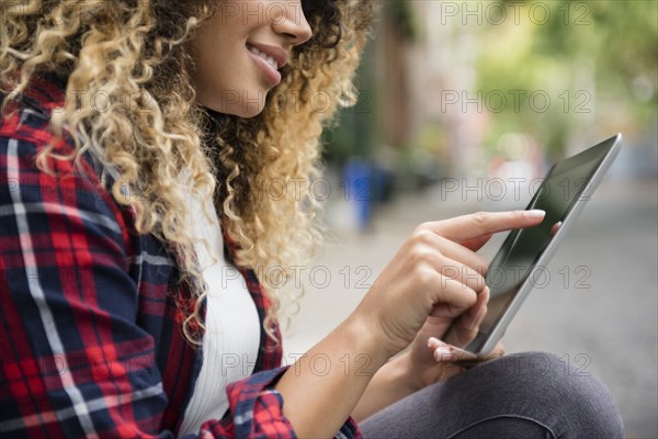 Mixed Race woman using digital tablet in city