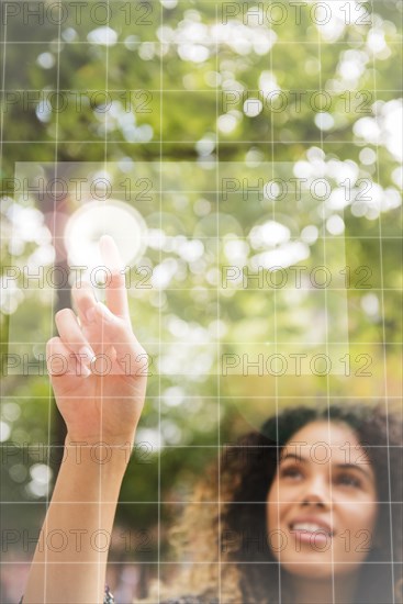 Mixed Race woman pointing to virtual screen outdoors