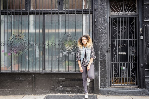 Mixed Race woman leaning on gated window in city