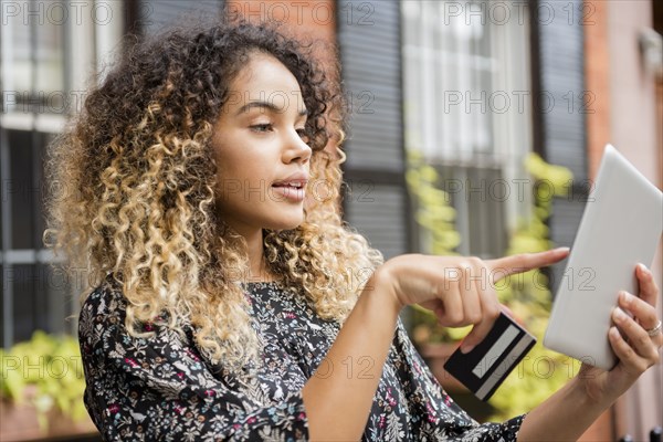 Mixed Race woman online shopping with digital tablet in city