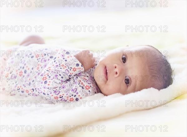 Portrait of Hispanic baby girl laying on blanket