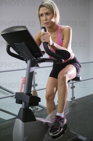 Mixed Race woman riding stationary bicycle