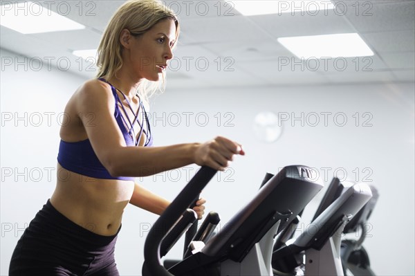 Mixed Race woman using elliptical machine