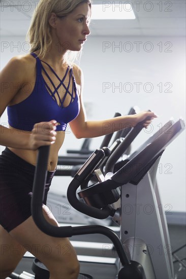 Mixed Race woman using elliptical machine