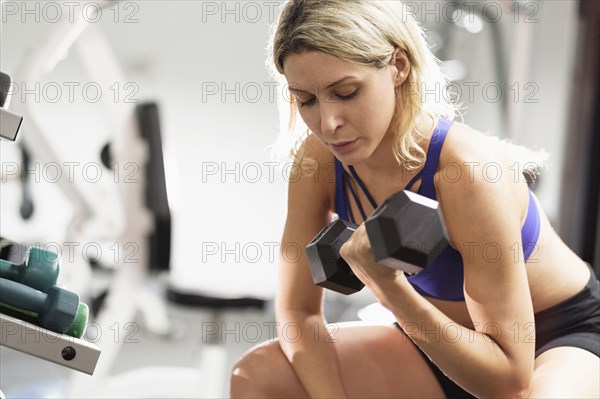 Mixed Race woman doing curls with dumbbell