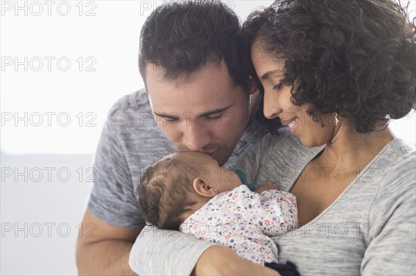 Hispanic father kissing baby daughter