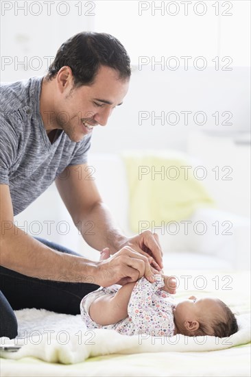 Hispanic father on bed playing with baby daughter