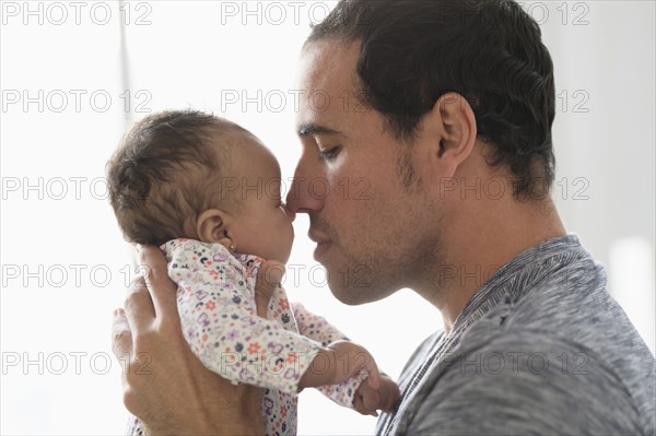 Hispanic father rubbing noses with baby daughter