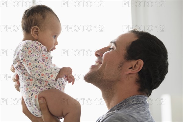 Hispanic father lifting baby daughter