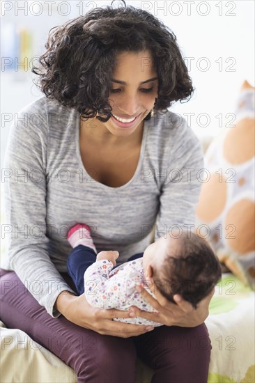 Hispanic mother cradling baby daughter