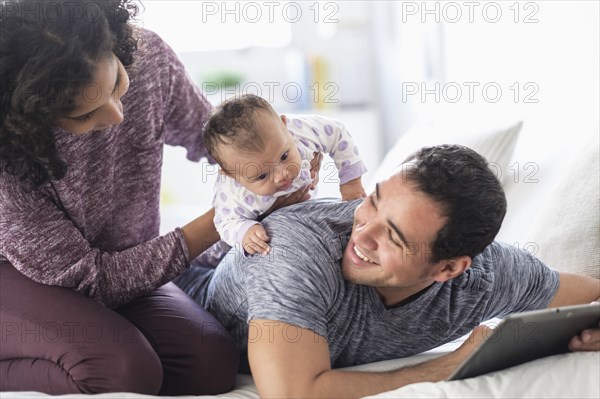 Hispanic mother holding baby daughter on back of father