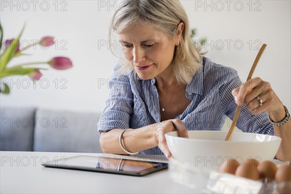 Caucasian woman baking with recipe on digital tablet