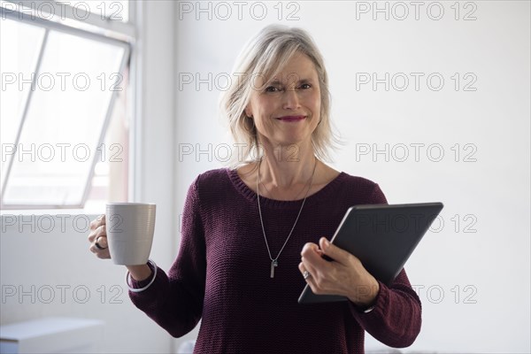 Portrait of Caucasian businesswoman holding coffee cup and digital tablet