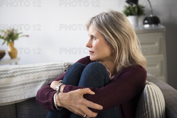 Worrying Caucasian woman hugging legs