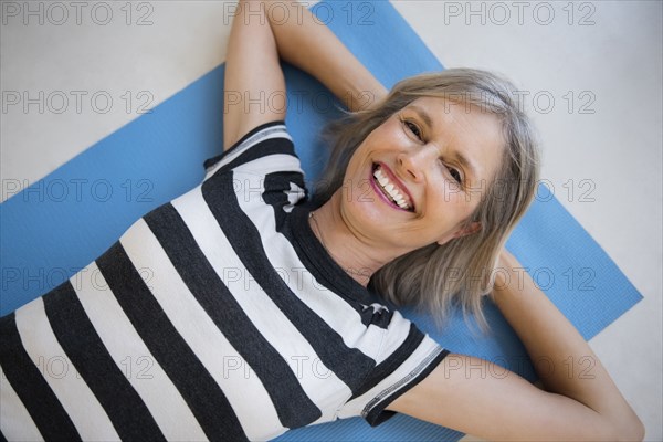 Smiling Caucasian woman laying on exercise mat