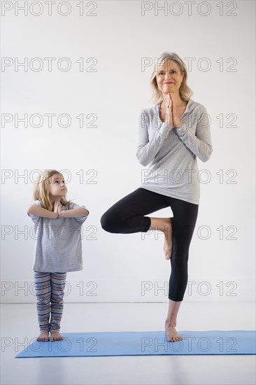 Caucasian granddaughter watching grandmother practicing yoga