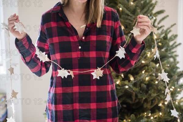 Caucasian woman holding Christmas ornaments on string