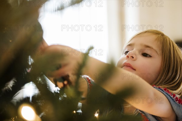 Caucasian girl hanging lights on Christmas tree