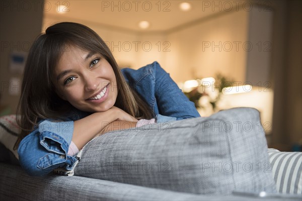 Smiling Mixed Race woman leaning on sofa