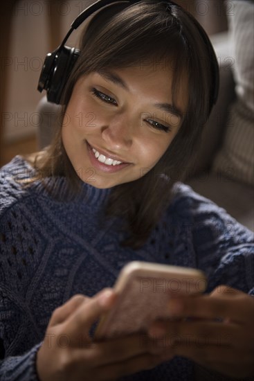 Mixed Race woman listening to cell phone with headphones