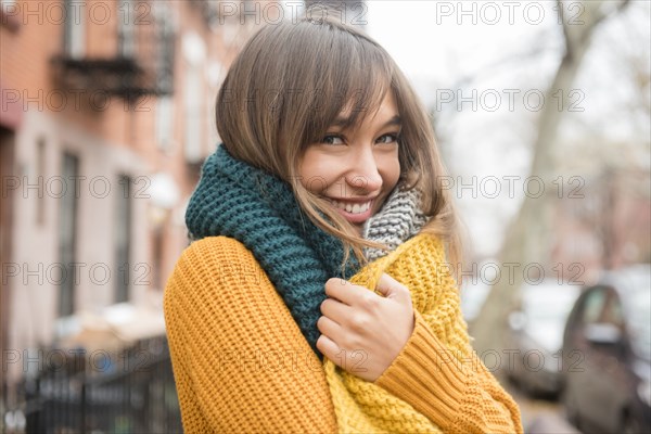 Portrait of smiling Mixed Race woman wearing scarf in city