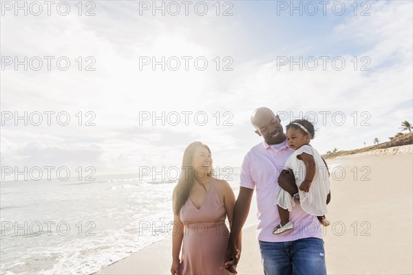 Couple walking on beach with baby daughter