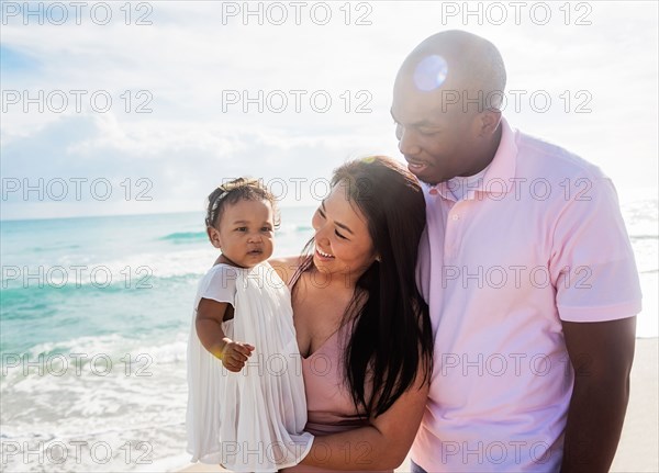 Couple admiring baby daughter on beach