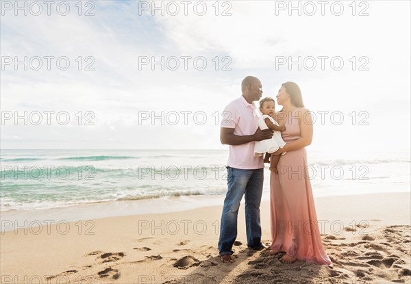 Couple holding baby daughter on beach
