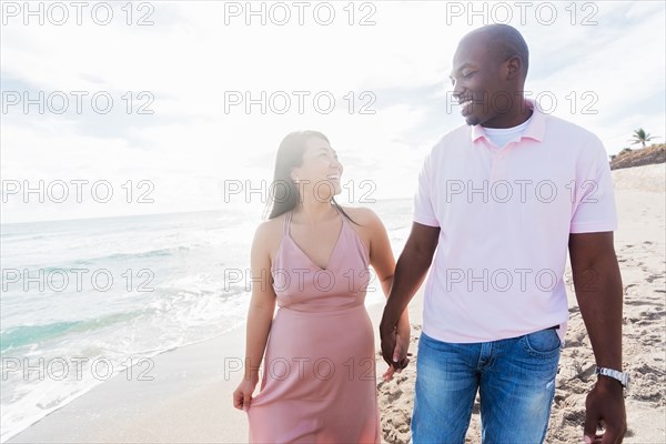 Couple holding hands walking on beach