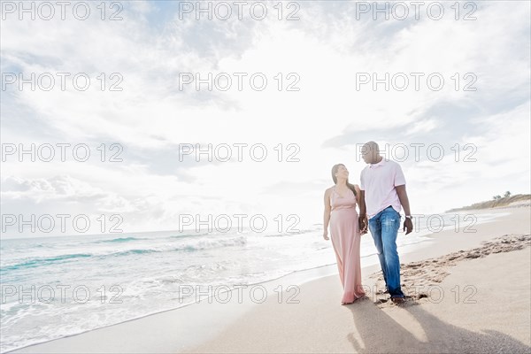 Couple holding hands walking on beach