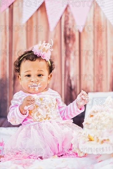 Messy Mixed Race baby eating birthday cake