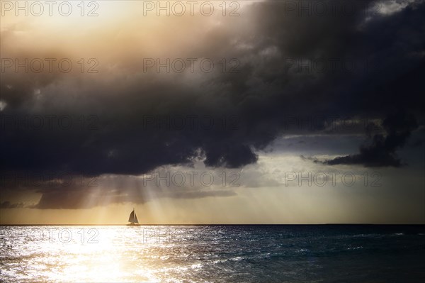 Sunbeams through storm clouds over sailboat