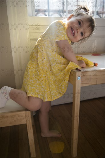 Portrait of smiling Caucasian baby girl leaning on table