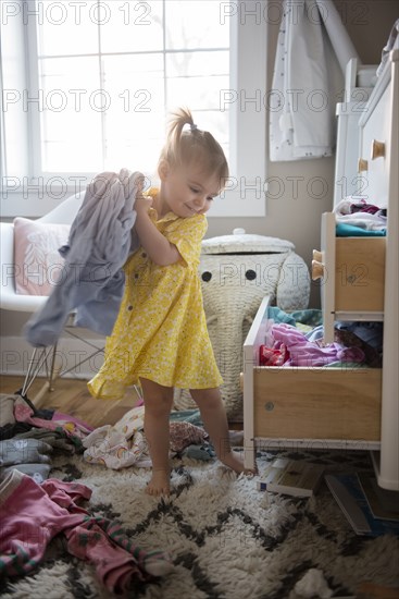 Caucasian baby girl removing clothing from dresser drawer