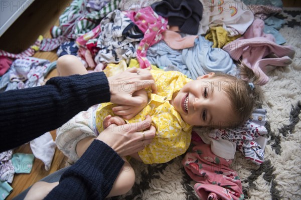 Hands of Caucasian mother tickling baby daughter on floor