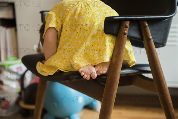 Barefoot Caucasian baby girl laying on chair