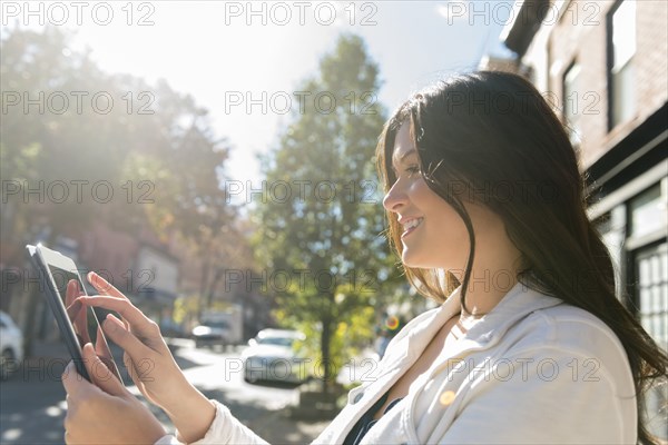 Caucasian woman using digital tablet in city