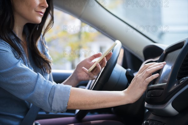 Caucasian woman in car holding cell phone programming journey