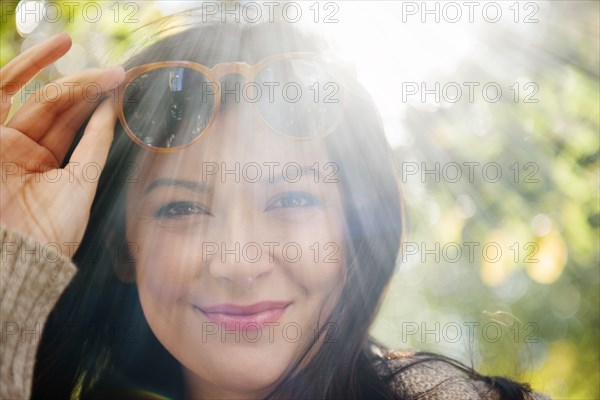 Sunbeams on Caucasian woman raising sunglasses