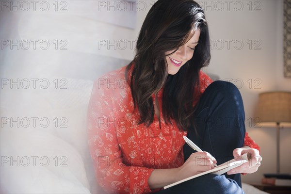 Smiling Caucasian woman writing on notepad