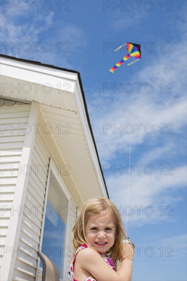 Caucasian girl flying kite near house