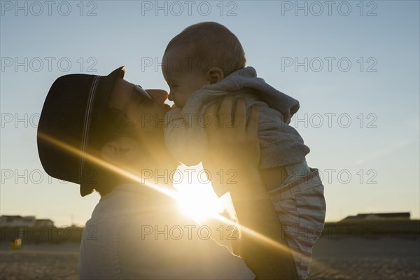 Sun beaming between Caucasian father and baby son