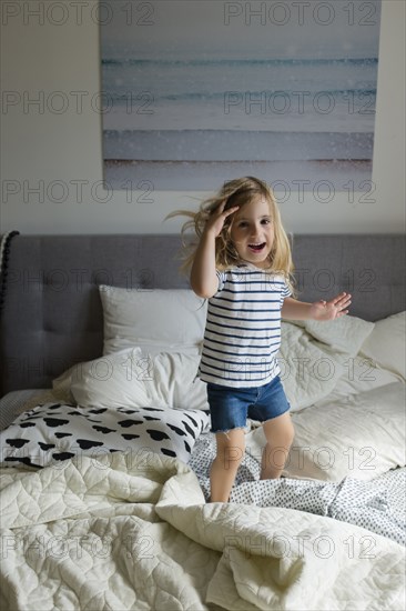 Caucasian girl jumping on bed